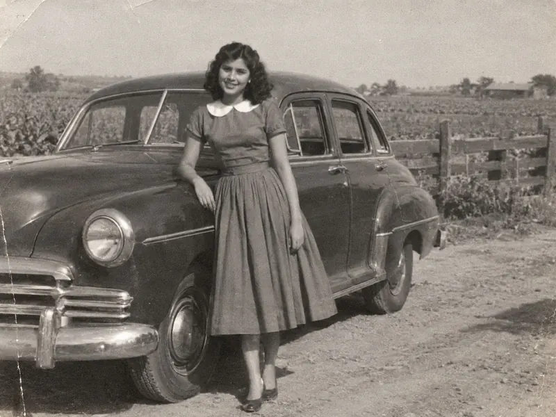 AI colorizing picked a blue dress for a 1950s photo of a girl beside a car